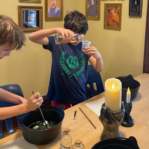 A young wizard pours a potion at a Harry Potter party.