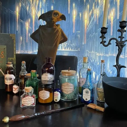 Potion bottles and candles on a table set for a wizarding party.