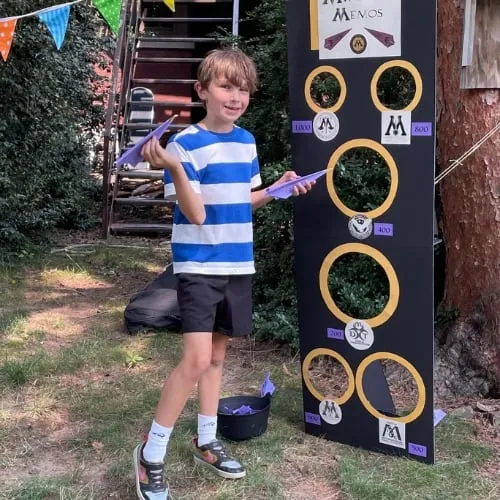 A camper with a broom beside a homemade Quidditch hoop.