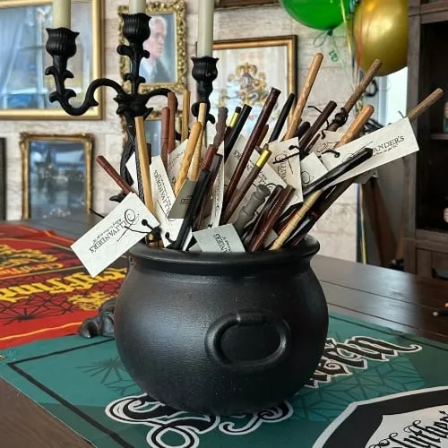 A cauldron full of handmade wands on a table set for a Harry Potter party.