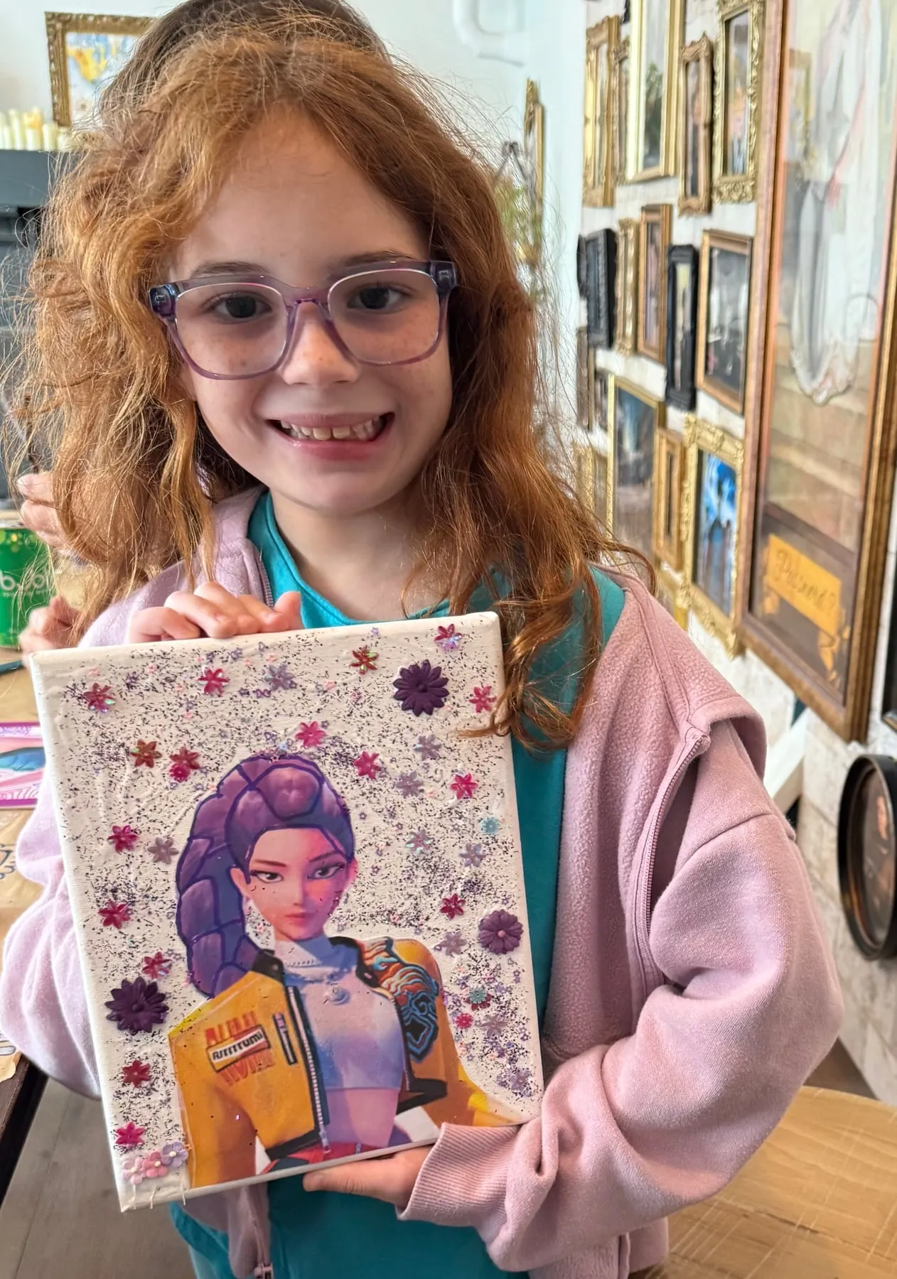 A smiling girl shows off her sparkly Huntrix idol portrait.