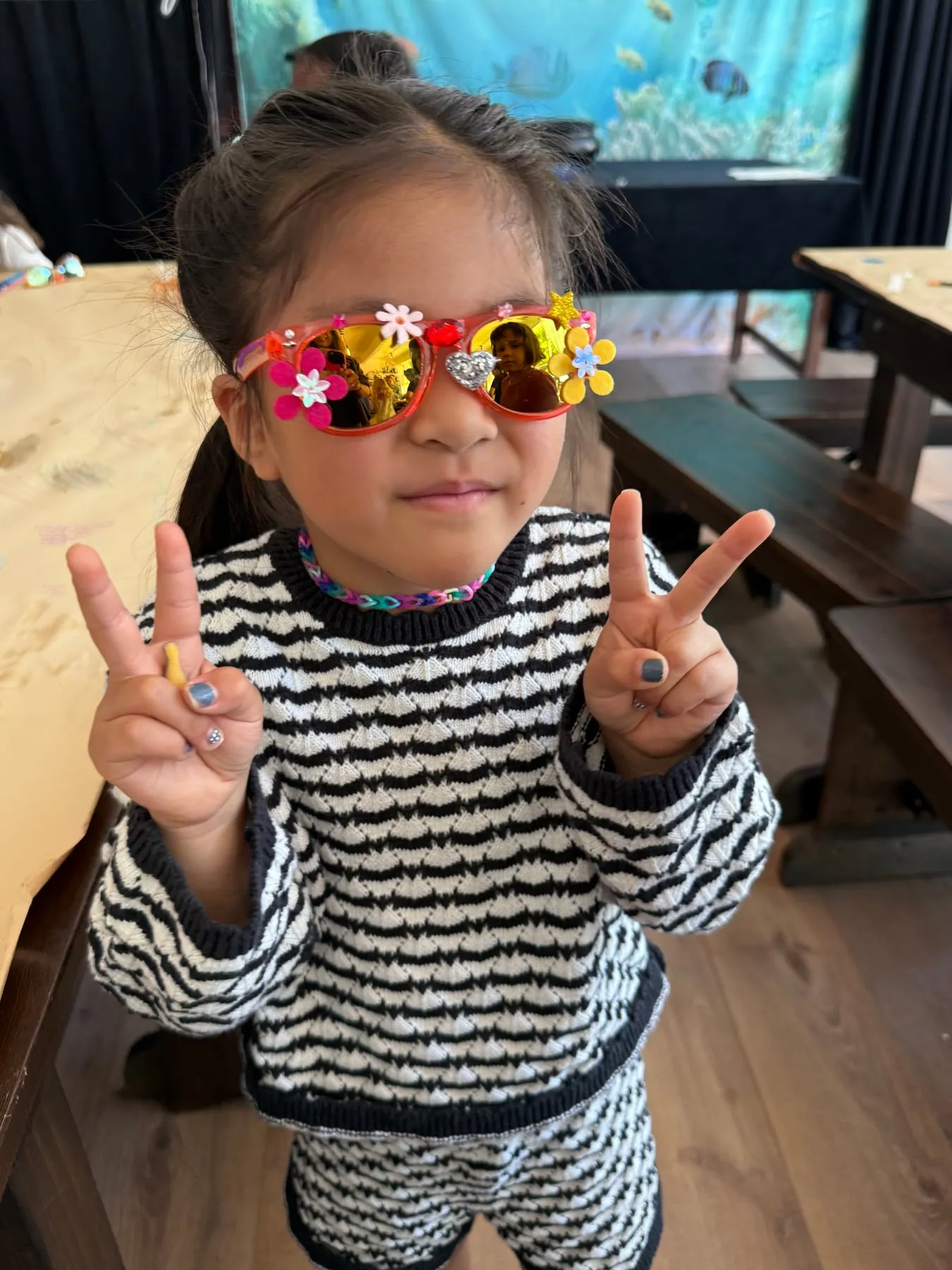 A girl in flower and gem sunglasses she decorated at an Under the Sea party.