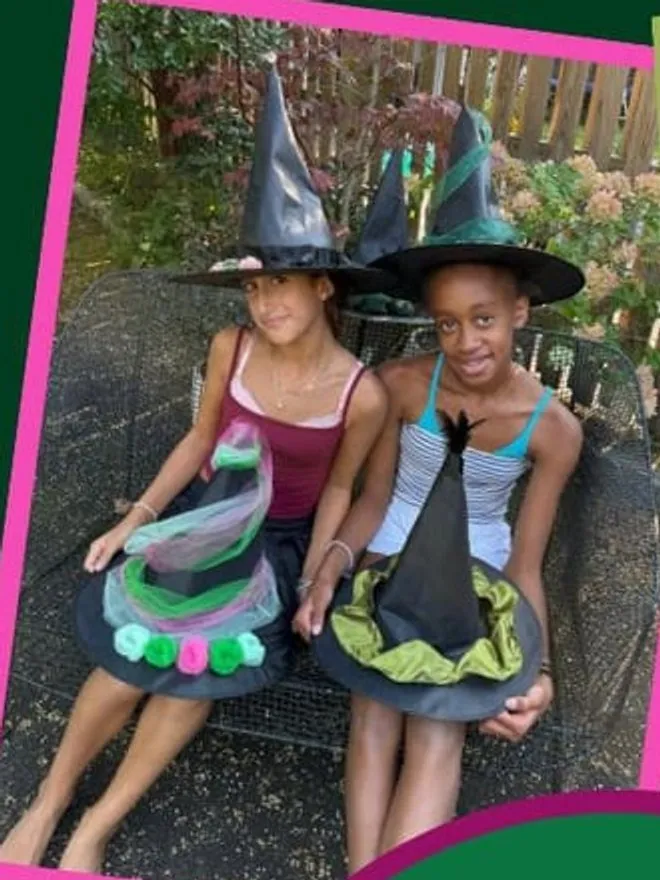 Two girls wearing the Elphaba hats they decorated at Wand & Willow.